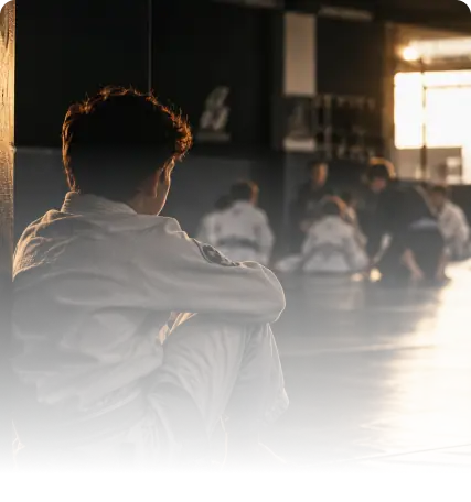 Aluno sentado à margem de uma aula de artes marciais